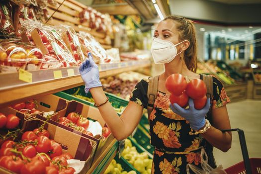 Shot of a young woman is wearing N95 protective mask while buying groceries in supermarket during Covid-19 pandemic.