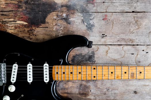 Detail of Black Electric Guitar on a wood background.