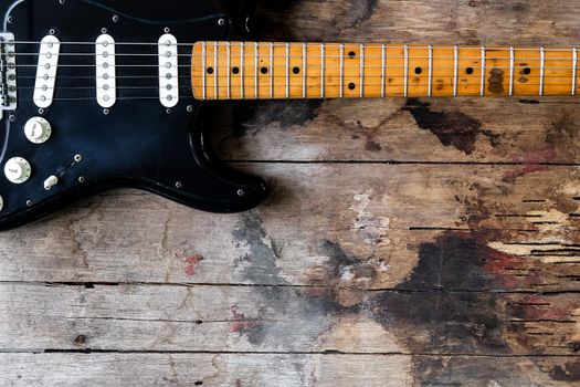 Detail of Black Electric Guitar on a wood background.