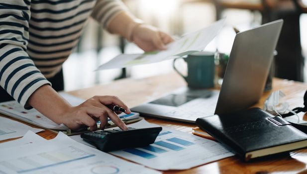 Close up accountant working on desk using calculator for calculate finance report at home office.