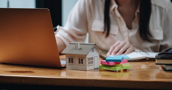 Real estate woman with house model on working desk for investment to buying property.