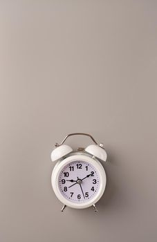Time management, punctuality, business metaphors. White vintage alarm clock with nine ten on gray background, flat lay top view, copy space