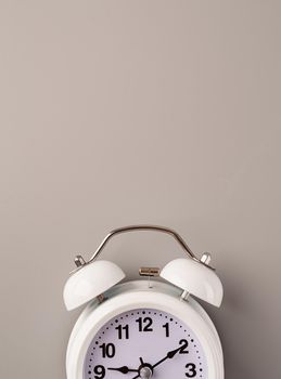 Time management, punctuality, business metaphors. White vintage alarm clock with nine ten on gray background, flat lay top view, copy space