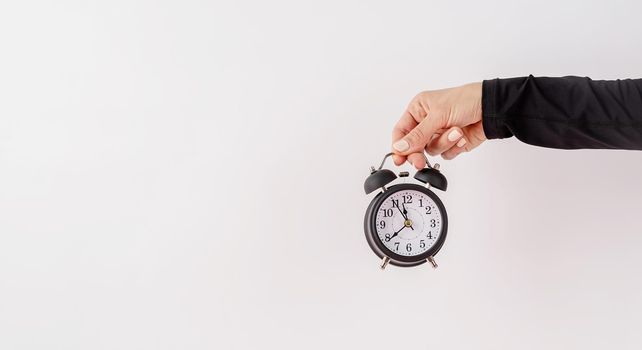 Time management, punctuality, business metaphors. Female hand holding white alarm clock on white background with copy space