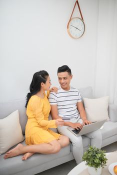 Happy young couple sitting on sofa with laptop