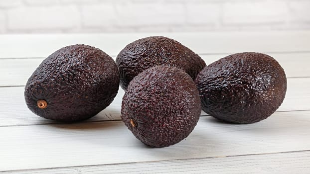 Dark brown avocados ( Bilse cultivar )  on white boards desk.