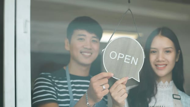 Open. barista, waitress, waiter turning open sign board on glass door in modern cafe coffee shop, cafe restaurant, retail store, small business owner, food and drink concept.
