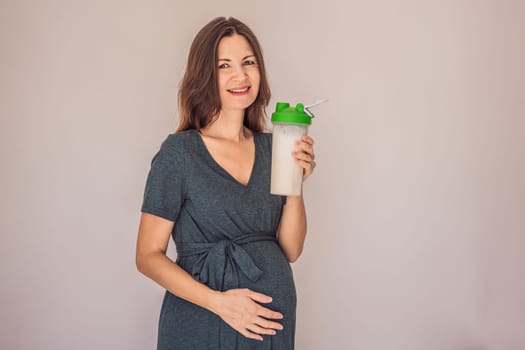Energetic and fit pregnant woman after 40 enjoying a protein shake for a nourishing boost during her pregnancy journey. Embracing health and wellness for a thriving baby and mom.