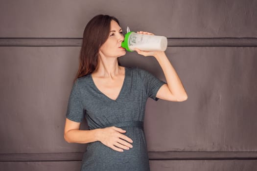 Energetic and fit pregnant woman after 40 enjoying a protein shake for a nourishing boost during her pregnancy journey. Embracing health and wellness for a thriving baby and mom.