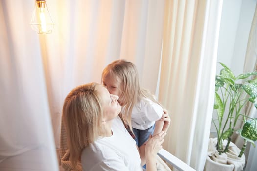 Happy loving family with mother and daughter having hugs in living room. Woman mom and small child girl inside of home