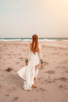 woman sea white dress. Model in boho style in a white long dress and silver jewelry on the beach. Her hair is braided, and there are many bracelets on her arms