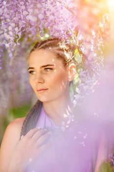 Woman wisteria lilac dress. Thoughtful happy mature woman in purple dress surrounded by chinese wisteria.