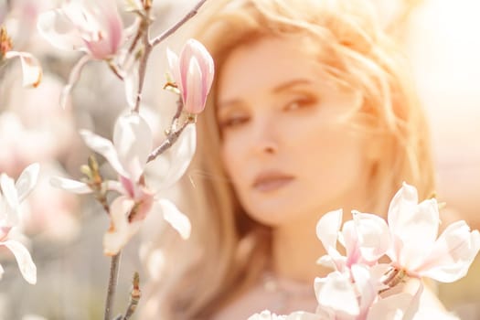 Magnolia woman portrait. Happy middle aged woman enjoying the smell in a blooming spring garden. Beautiful magnolia bushes, large flowers