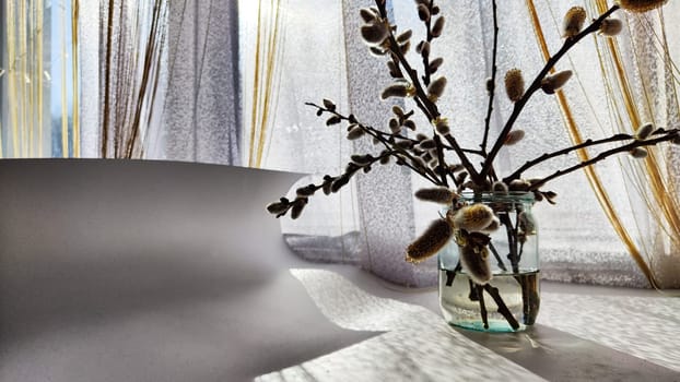 A bouquet made of willow branches on table near the window with curtains and daylight sun. The concept of spring. Preparation for the religious holiday of Easter