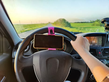 Hand of woman on the steering wheel of car during a trip. The female driver travels alone. Trip in summer time