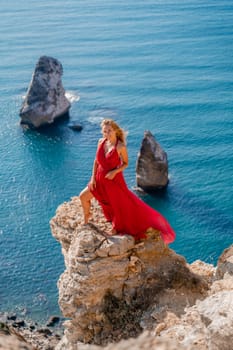 A woman in a red flying dress fluttering in the wind, against the backdrop of the sea