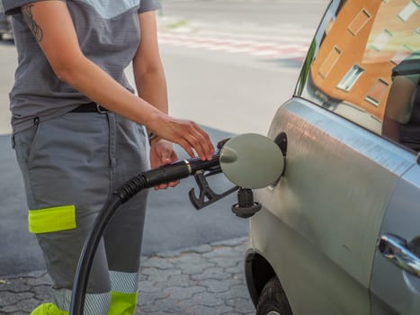 Cremona, Italy - July 3 2023 caucasian service woman at Eni Agip city fuel station pumping petrol to a customer car