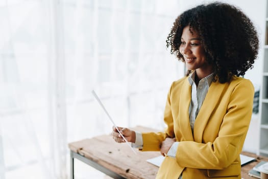 Beautiful young African american businesswoman using laptop computer and paperworks with planning working on financial document, tax, exchange, accounting and Financial advisor.