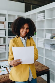 Beautiful young African american businesswoman using laptop computer and paperworks with planning working on financial document, tax, exchange, accounting and Financial advisor.