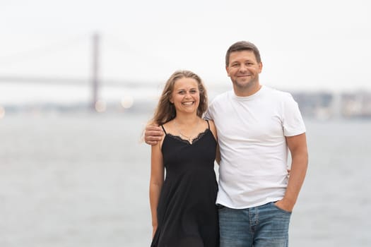 Cute adult married couple standing on the pier. Mid shot