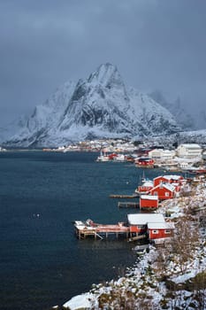 Reine fishing village on Lofoten islands with red rorbu houses in winter with snow. Norway