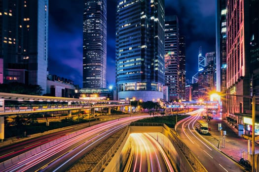 Street traffic in Hong Kong at night. Office skyscraper buildings and busy traffic on highway road with blurred cars light trails. Hong Kong, China