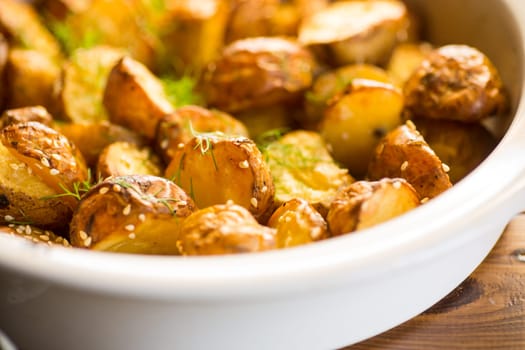 potatoes baked with sesame seeds, herbs and spices in the oven in a ceramic form.