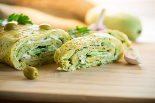 vegetable zucchini roll with garlic cheese filling inside, on a wooden board.