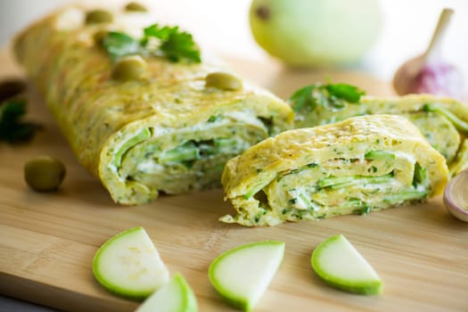 vegetable zucchini roll with garlic cheese filling inside, on a wooden board.