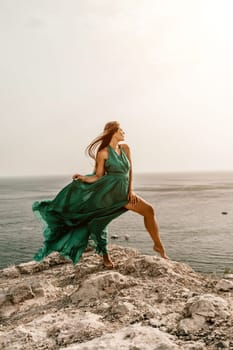 Woman sea trevel green dress. Side view a happy woman with long hair in a long mint dress posing on a beach with calm sea bokeh lights on sunny day. Girl on the nature on blue sky background