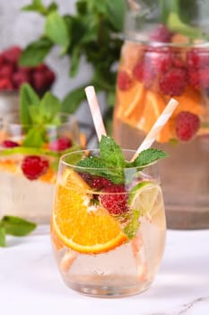 Summer Sangria cocktail or lemonade with raspberry, orange and mint. Refreshing organic non-alcoholic, Detox vitaminized healthy drink, fruit in a in a glass. Quench your thirst on a hot day.