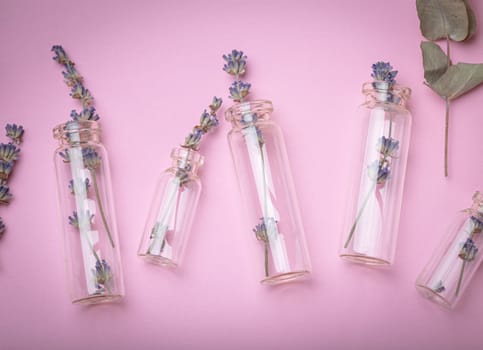 Lavender sprigs and eucalyptus in glass test tubes on purple simple background top view, beauty concept of cosmetology, bode and skincare, aromatherapy. Botanical natural cosmetic ingredient.