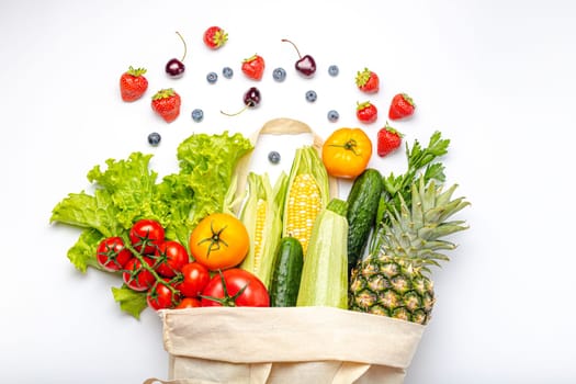 Grocery shopping. Different fresh fruit and vegetables in a textile shopper bag on white background, healthy food from supermarket or delivery concept..