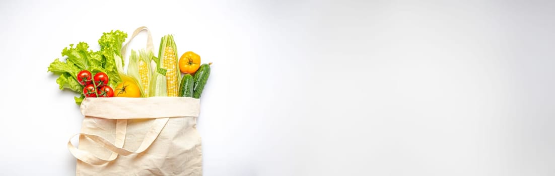 Vegetarian grocery shopping. Different fresh vegetables in a textile shopper bag on white background, healthy vegan food from supermarket or delivery concept, copy space.