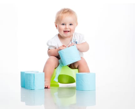 little baby sitting on a pot and keeps the toilet paper. studio photo on white background