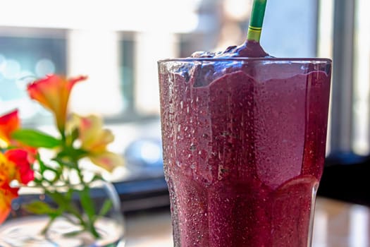 black currant smoothie in glassful on dark background.