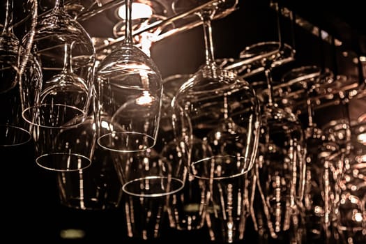 transparent wine glasses for drinks hang over the bar counter on the background of the interior of the cafe. Close-up