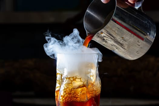 Whisky Smoke. Smoking whiskey with ice and orange on a dark background. Cognac with smoking branch of lavender. Experimental alcoholic cocktail in a glass with smoking rosemary.