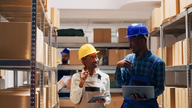 African american team counting warehouse goods on racks and planning order shipment, man and woman analyzing list of merchandise in storage room. Cargo logistics and inventory.