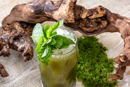 Glass of cocktail green fairy with lemon and absinthe at bar stand festive background