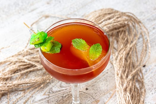 Glass of orange cocktail decorated with orange at bar counter background.