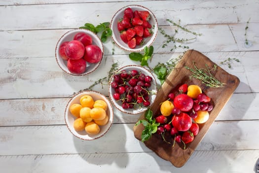 Fresh berries and fruits on a old-fashioned wooden plate on rotten stump. Countryside. Outdoor