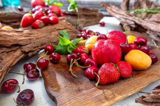 Fresh berries and fruits on a old-fashioned wooden plate on rotten stump. Countryside. Outdoor