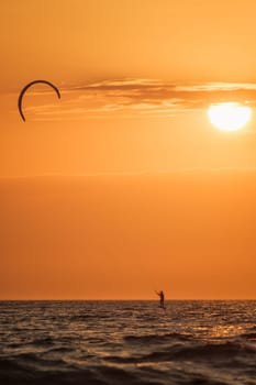 Foiling kiteboarding kitesurfing kiteboarder (kitesurfer) silhouette in the Atlantic ocean on sunset. Fonte da Telha beach, Costa da Caparica, Portugal