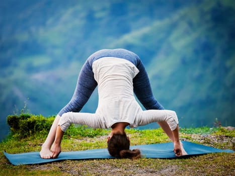 Yoga exercise outdoors - woman doing Ashtanga Vinyasa Yoga asana Prasarita padottanasana D - wide legged forward bend pose outdoors. Vintage retro effect filtered hipster style image.