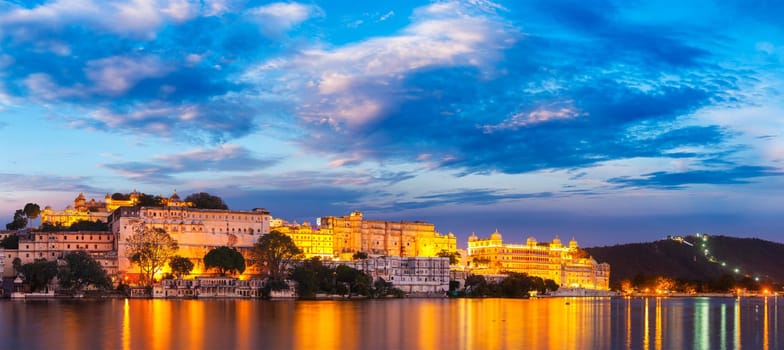 Panorama of famous romantic luxury Rajasthan indian tourist landmark - Udaipur City Palace in the evening twilight with dramatic sky - panoramic view. Udaipur, India