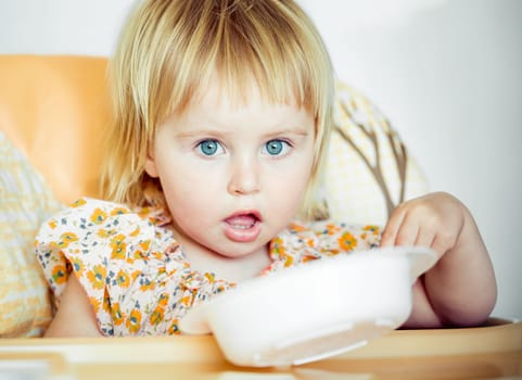 cute baby girl is holding a spoon and going to eat