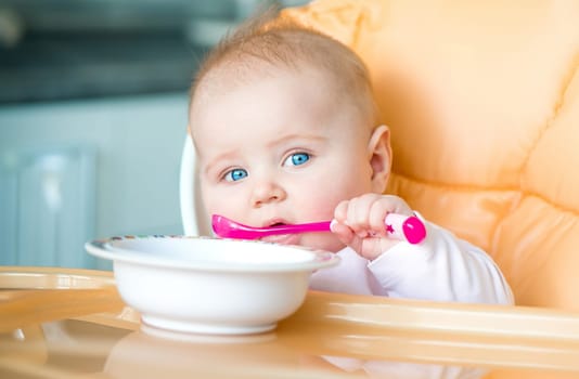 smiley baby girl is holding a spoon in her mouth and going to eat