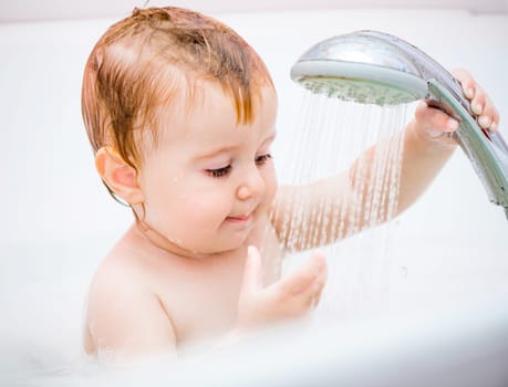 cute 1 year-old girl bathes in a shower