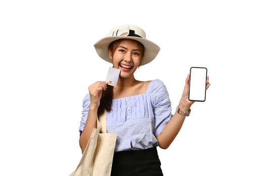 Excited woman tourist holding credit card and showing smartphone with blank screen. Holiday, vacation, traveling concept.